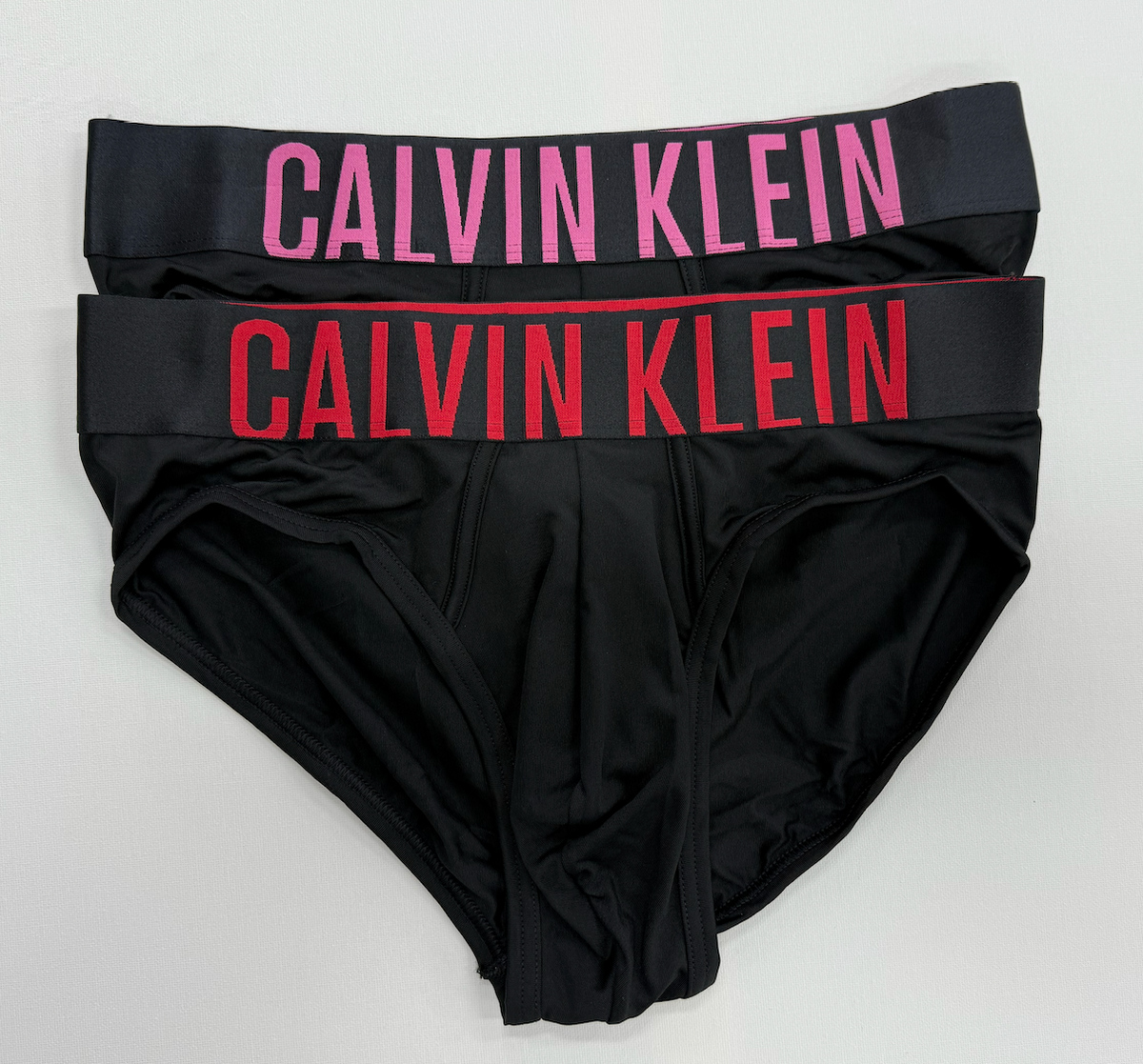 Black Calvin Klein underwear with red and pink branding on a white background